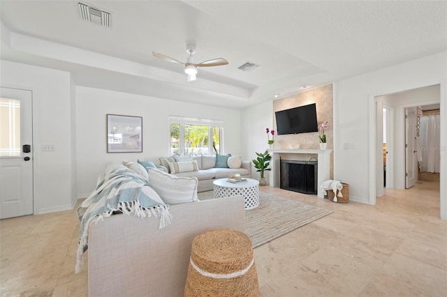 living room with visible vents, a large fireplace, baseboards, and a raised ceiling