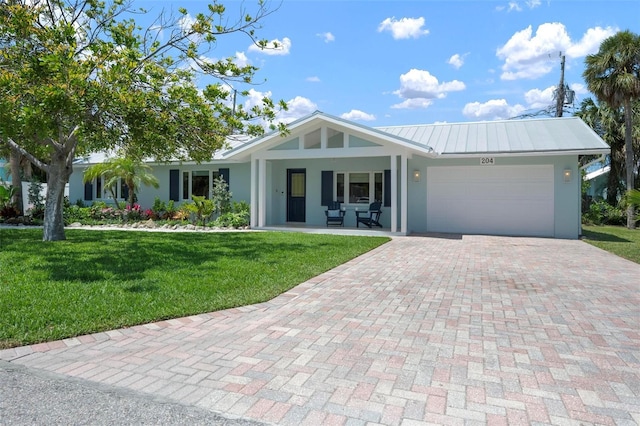 ranch-style house featuring stucco siding, decorative driveway, an attached garage, a front yard, and metal roof