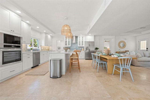 kitchen with a center island, appliances with stainless steel finishes, a breakfast bar, a tray ceiling, and recessed lighting