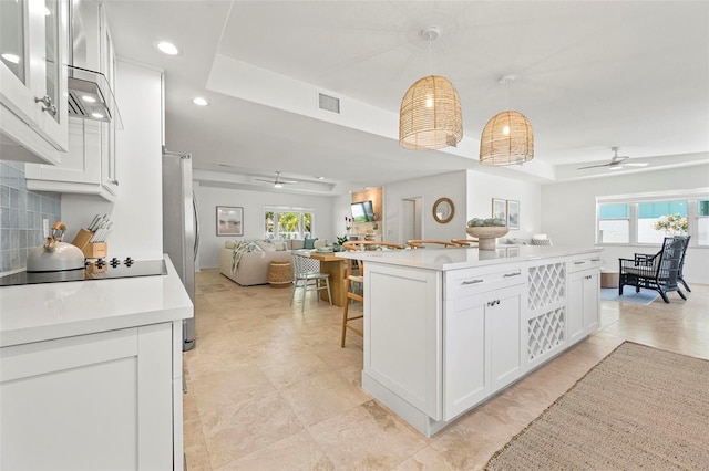 kitchen with ceiling fan, a tray ceiling, visible vents, open floor plan, and black electric cooktop
