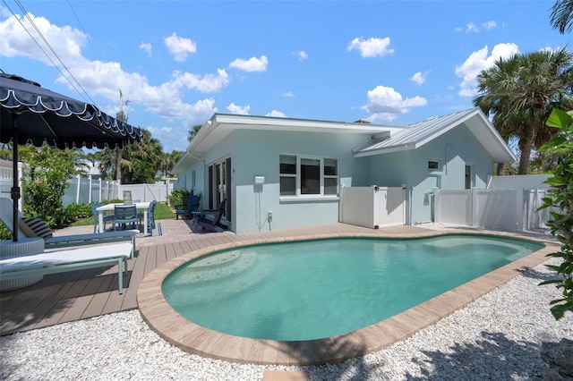 back of property featuring a fenced in pool, outdoor dining area, stucco siding, and a wooden deck