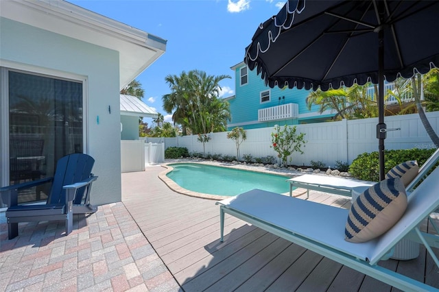 view of pool with a fenced backyard, a wooden deck, a fenced in pool, and a patio