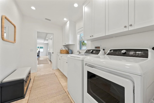 clothes washing area with cabinet space, visible vents, washing machine and clothes dryer, and plenty of natural light