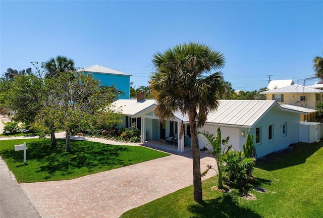 view of front of home with metal roof, a front yard, a standing seam roof, and decorative driveway