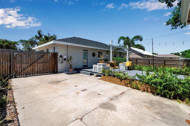 rear view of property featuring a patio area, fence, and a gate