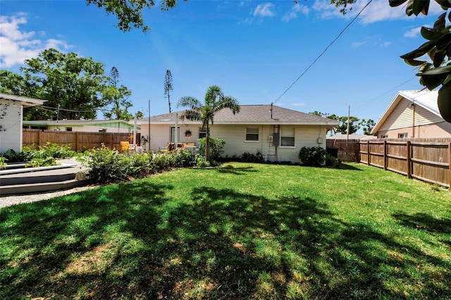 rear view of house featuring a yard and a fenced backyard