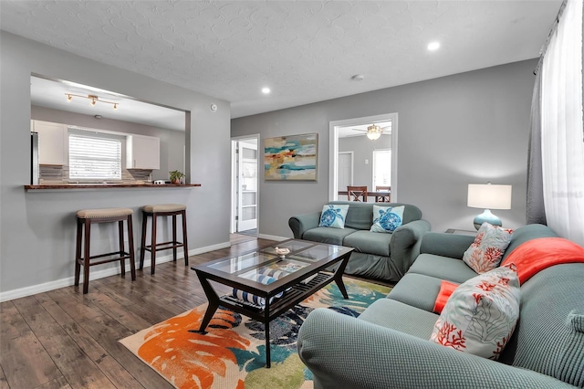 living area featuring dark wood-type flooring, baseboards, recessed lighting, and a textured ceiling