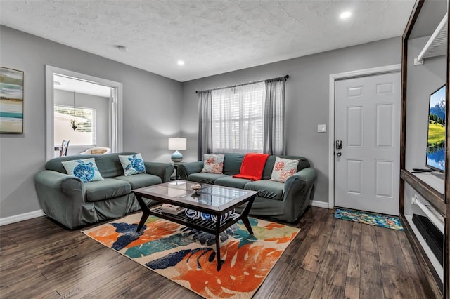living room featuring baseboards, a textured ceiling, and dark wood finished floors