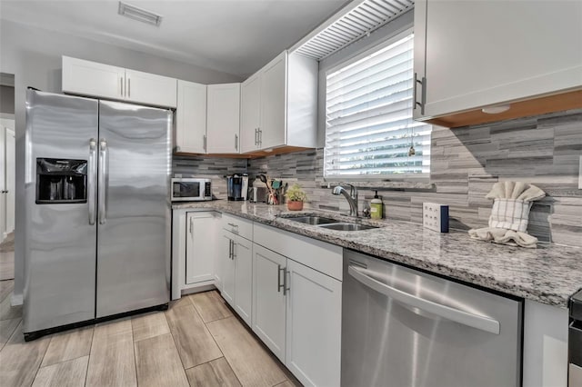 kitchen with a sink, visible vents, decorative backsplash, and stainless steel appliances