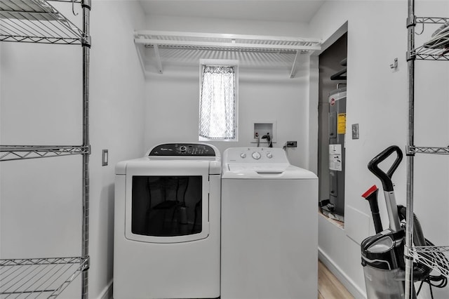 laundry room with laundry area, light wood finished floors, electric water heater, and washing machine and dryer