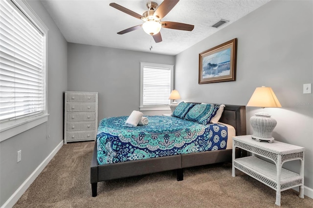 bedroom featuring baseboards, carpet flooring, a textured ceiling, a ceiling fan, and visible vents