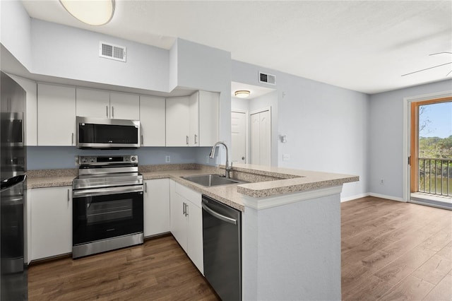 kitchen featuring stainless steel appliances, a peninsula, visible vents, and a sink