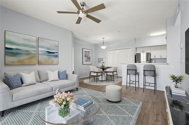 living room with baseboards, a ceiling fan, and wood finished floors