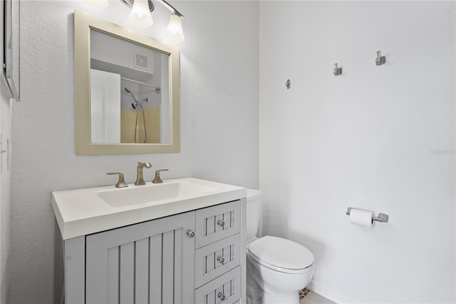 bathroom featuring toilet, vanity, visible vents, and a shower