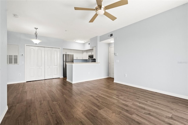 unfurnished living room with visible vents, baseboards, a ceiling fan, and dark wood-style floors