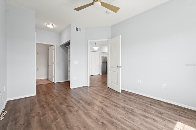 unfurnished bedroom featuring wood finished floors, freestanding refrigerator, baseboards, and visible vents