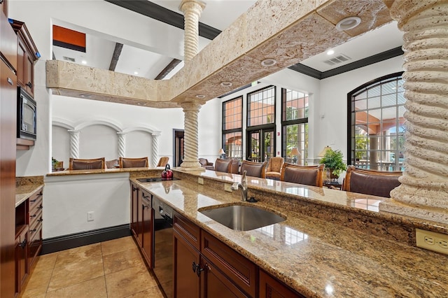 kitchen with black dishwasher, built in microwave, visible vents, ornate columns, and a sink