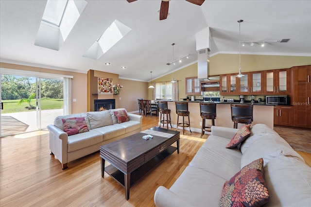 living room with light wood-style floors, visible vents, crown molding, and vaulted ceiling
