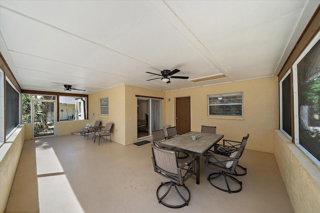 sunroom with outdoor dining space, ceiling fan, and concrete flooring