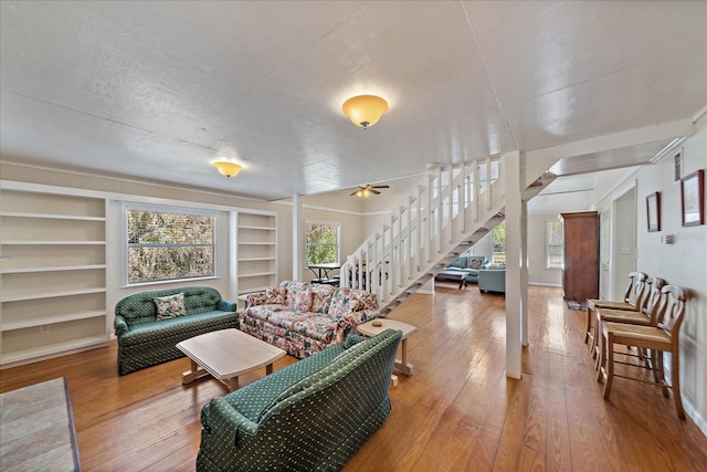 living room featuring built in shelves, ceiling fan, a textured ceiling, stairway, and hardwood / wood-style floors