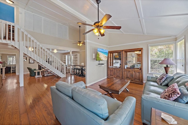 living area with a healthy amount of sunlight, a ceiling fan, wood finished floors, and stairs