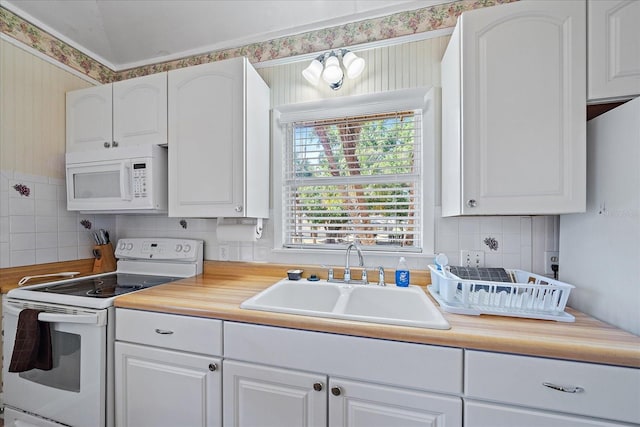 kitchen featuring wallpapered walls, a sink, white appliances, and white cabinets
