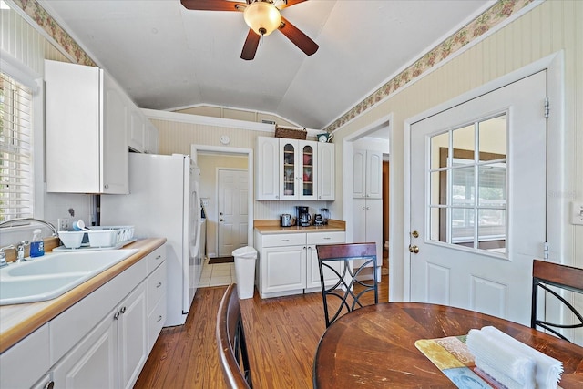kitchen with lofted ceiling, dark wood-style floors, white cabinets, ceiling fan, and a sink