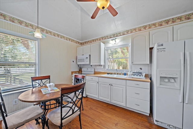 kitchen with a sink, white cabinetry, white appliances, and light wood-style floors
