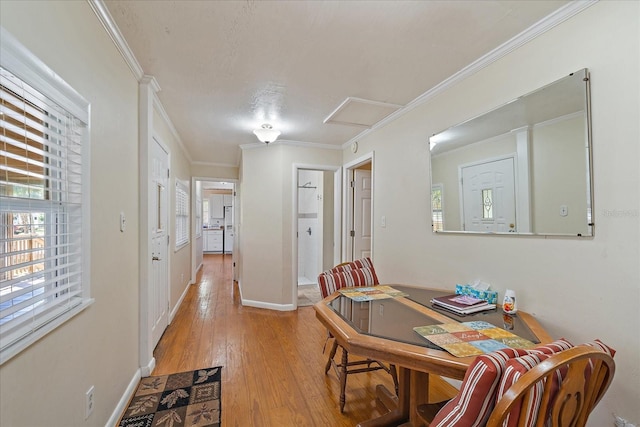 dining room featuring ornamental molding, baseboards, light wood finished floors, and attic access