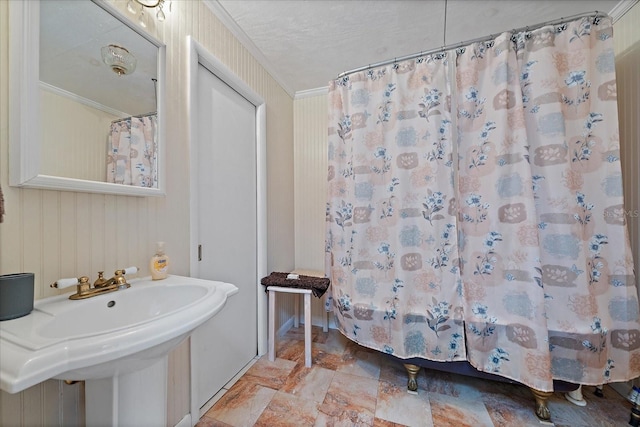 full bath with stone finish flooring, a shower with curtain, a sink, and crown molding