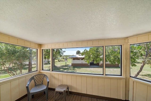 unfurnished sunroom featuring wood-type flooring and a textured ceiling