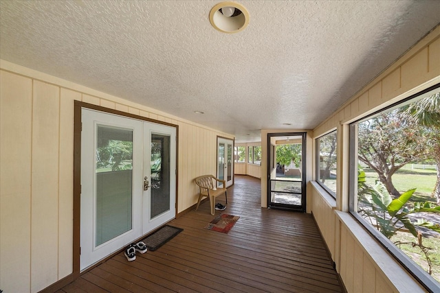 unfurnished sunroom with a decorative wall, french doors, hardwood / wood-style floors, and wooden walls