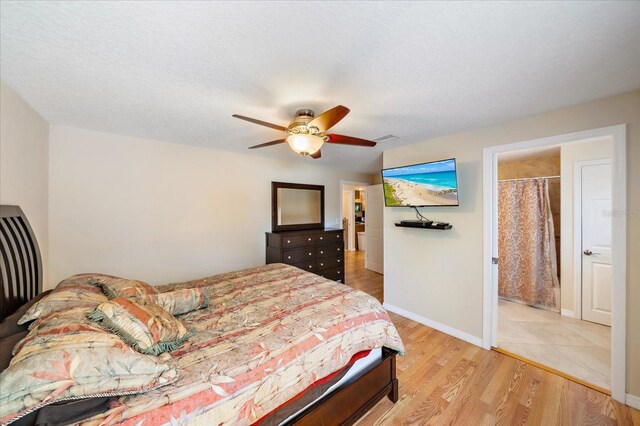 bedroom featuring baseboards, ceiling fan, light wood-style floors, and a textured ceiling