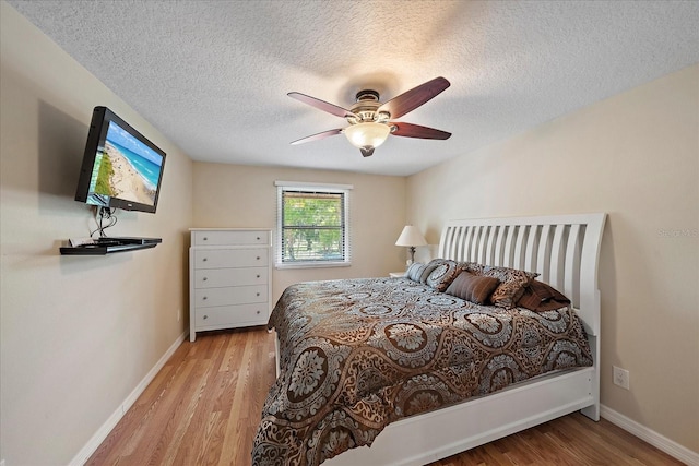 bedroom featuring baseboards, a textured ceiling, and wood finished floors