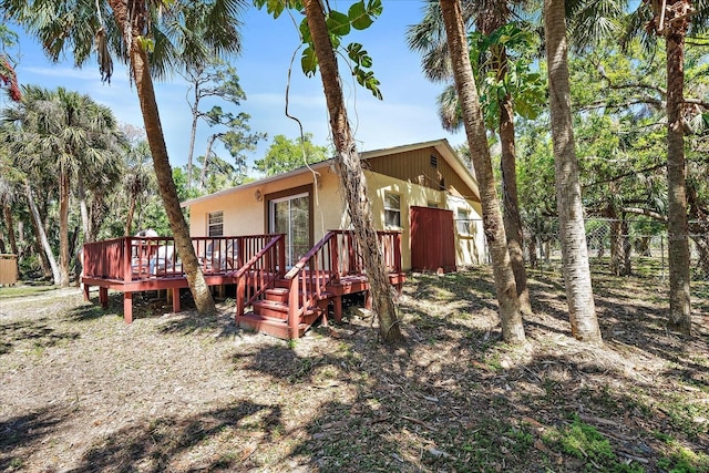 rear view of house featuring a deck and fence
