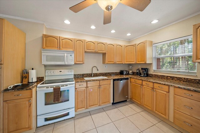 kitchen with white appliances, light tile patterned floors, crown molding, dark stone counters, and a sink