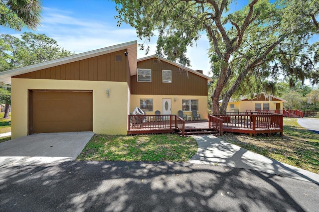 view of front facade with an attached garage, a deck, and driveway