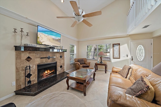 living area featuring visible vents, a tiled fireplace, ceiling fan, a towering ceiling, and tile patterned flooring