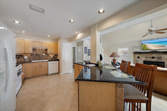 kitchen with visible vents, a breakfast bar, white appliances, and light brown cabinetry