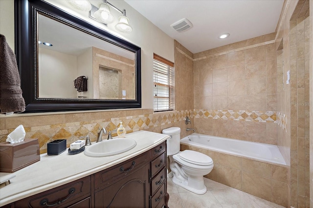 bathroom featuring vanity, tile patterned floors, toilet, visible vents, and tile walls