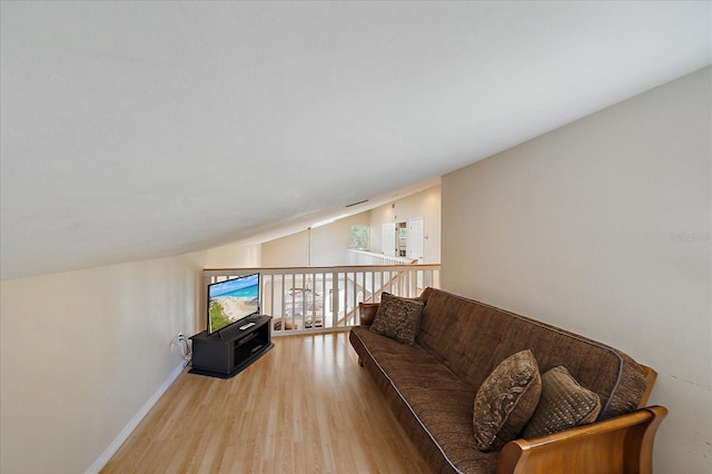living room with light wood-style flooring, baseboards, and lofted ceiling