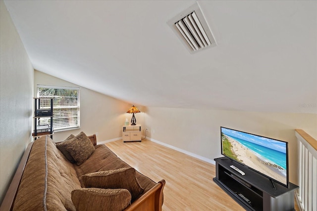 living room with lofted ceiling, visible vents, baseboards, and wood finished floors