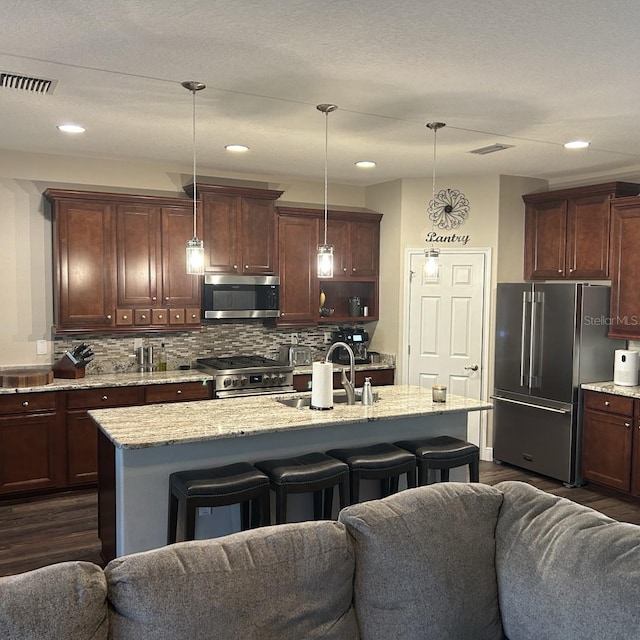 kitchen with premium appliances, dark wood-style flooring, a sink, and open floor plan