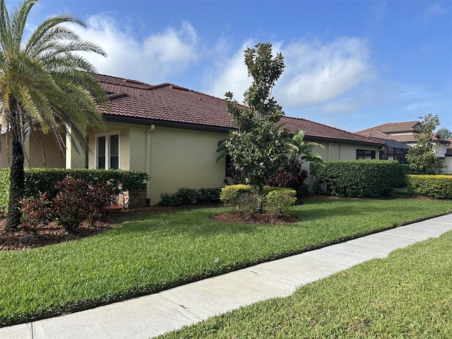 4622 Grand Lakeside Dr, Palm Harbor, FL 34684 - view of property exterior featuring stucco siding, a yard, and a tiled roof