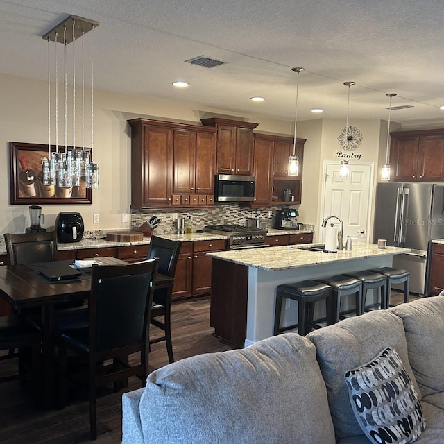 4622 Grand Lakeside Dr, Palm Harbor, FL 34684 - kitchen featuring premium appliances, open floor plan, dark wood-type flooring, decorative backsplash, and light stone countertops