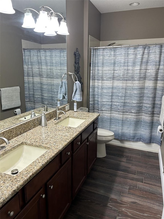 4622 Grand Lakeside Dr, Palm Harbor, FL 34684 - bathroom with toilet, wood finished floors, double vanity, and a chandelier