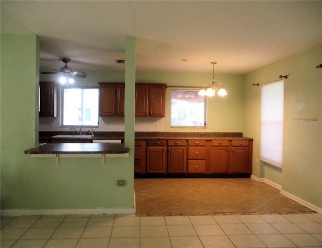 6339 Pontiac Ln, North Port, FL 34287 - kitchen with dark countertops, a kitchen breakfast bar, brown cabinetry, a peninsula, and a chandelier