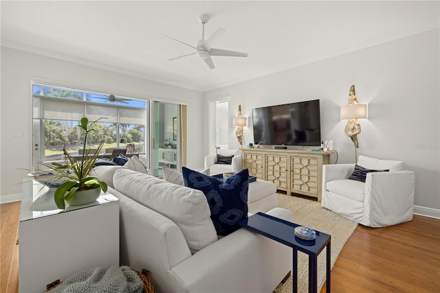 living area with baseboards, a ceiling fan, ornamental molding, and wood finished floors