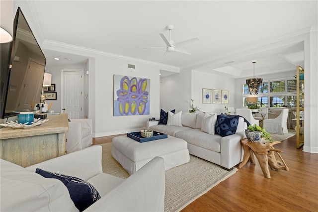 living room featuring visible vents, ceiling fan with notable chandelier, crown molding, and wood finished floors