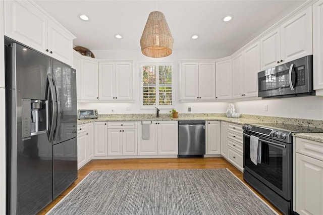 kitchen with light wood-style floors, white cabinetry, recessed lighting, appliances with stainless steel finishes, and a sink